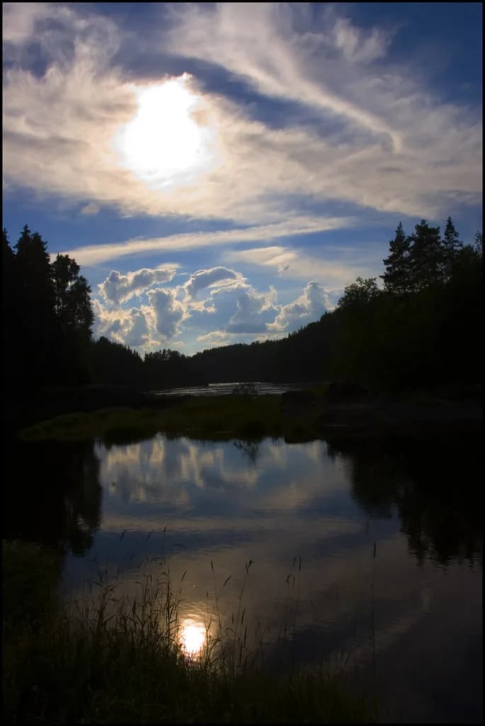 The Glomma river reflecting a dusky sky, lined with silhouetted trees.