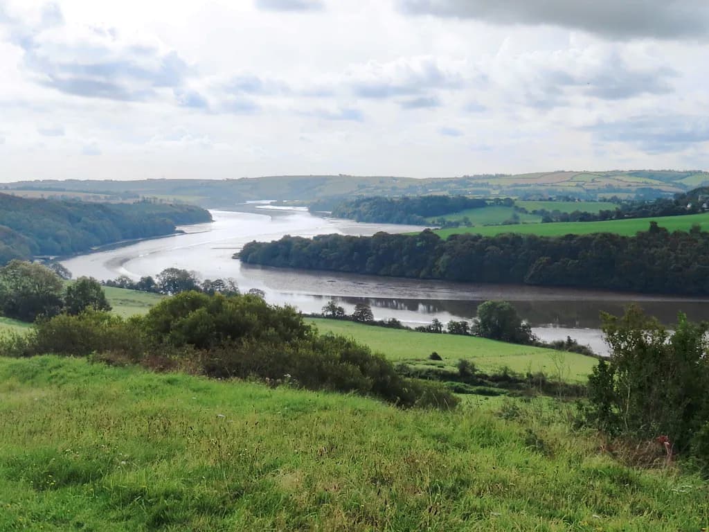 Wide tidal reach of the Bandon River curving through green farmland and woodland near Kinsale, County Cork, Ireland.