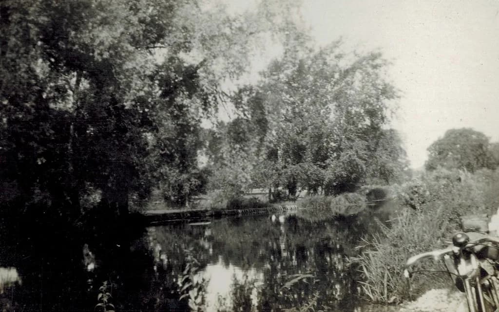 Vintage black-and-white photograph of the River Wylye, with overhanging trees reflected in still water.