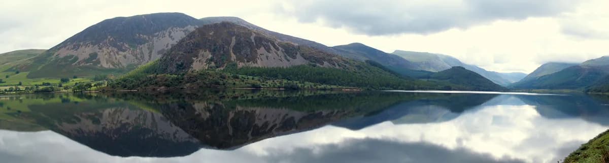 Panoramic view of Ennerdale Water lake with fells reflected in the still water