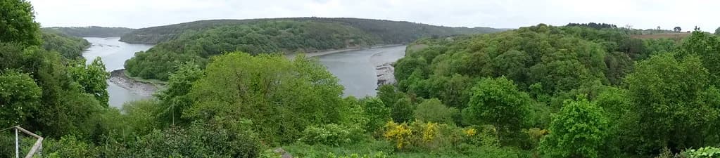 A wide panoramic view of the wooded Trieux river valley with the tidal river visible below.