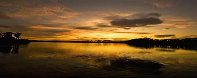 Wide panoramic view of sunset colours reflected in Knockaderry Reservoir, County Waterford, Ireland