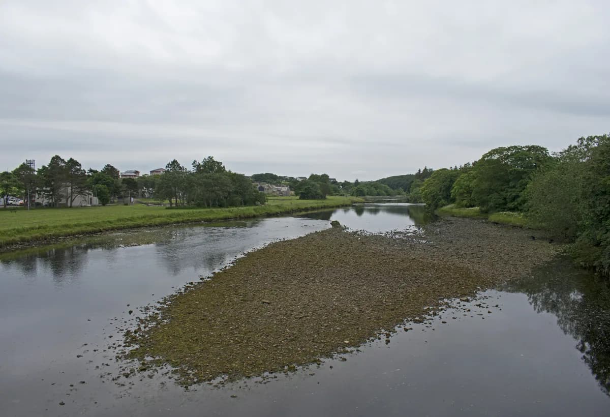A view upstream along the River Thurso from Thurso Bridge in Caithness, Scotland, with open water and low countryside banks.