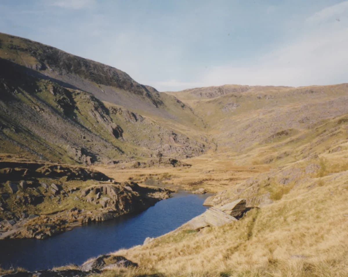Deep blue upland reservoir (Llyn Cwm Foel) set in a rocky valley with a mountain, Moel Boethwel, behind it, Snowdonia.