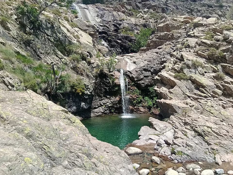 A waterfall on the Golo river tumbling into an emerald pool surrounded by granite boulders in the Corsican mountains