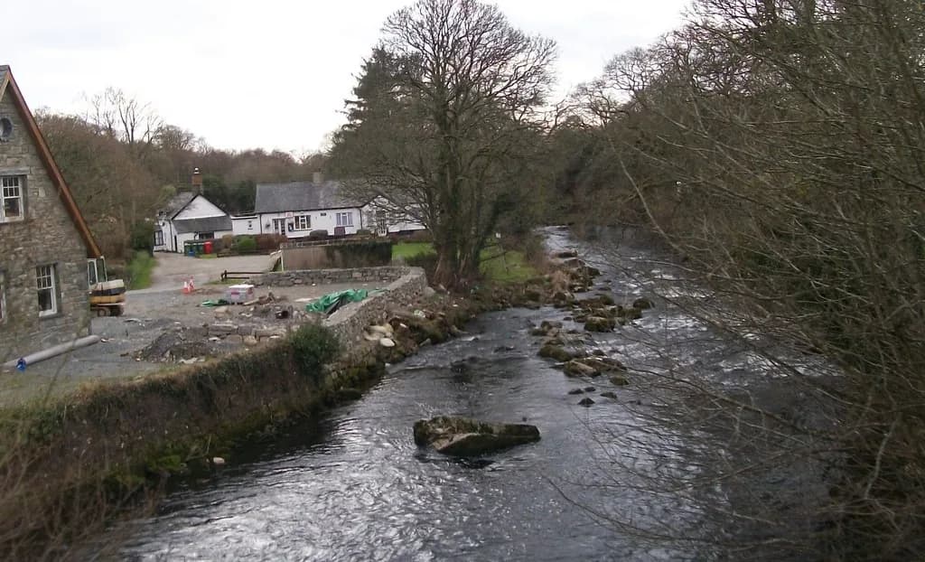 The Afon Dwyfor river flowing below the bridge at Llanystumdwy, Gwynedd, Wales, lined with trees.