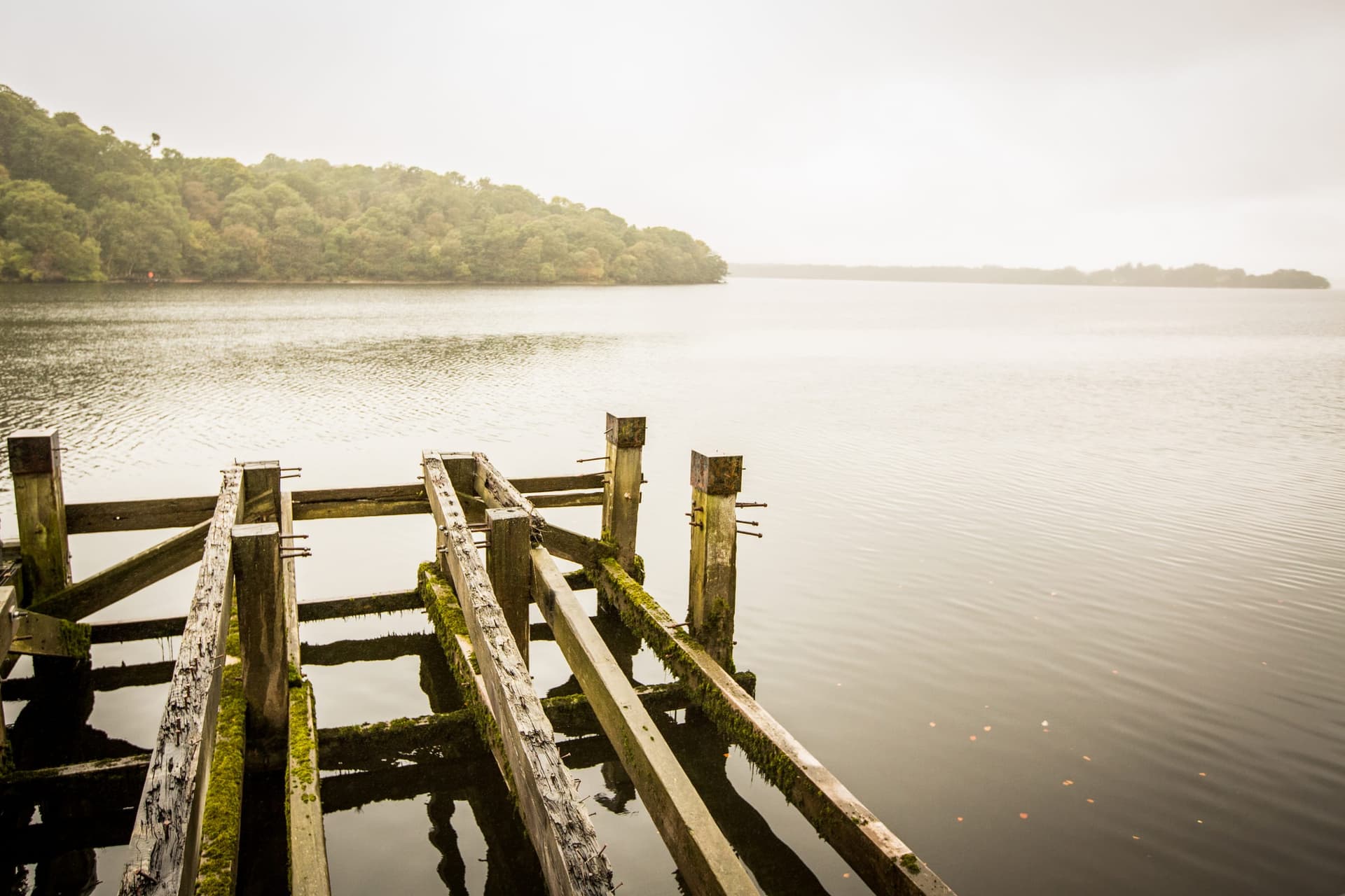 Balmaha Pier on Loch Lomond with boats moored alongside, open loch water stretching to wooded islands and hills.